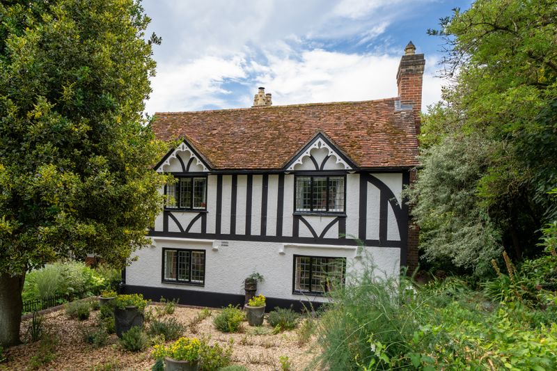 Explore a picturesque Tudor style cottage nestled in the rural village of Latimer, England, surrounded by lush greenery.