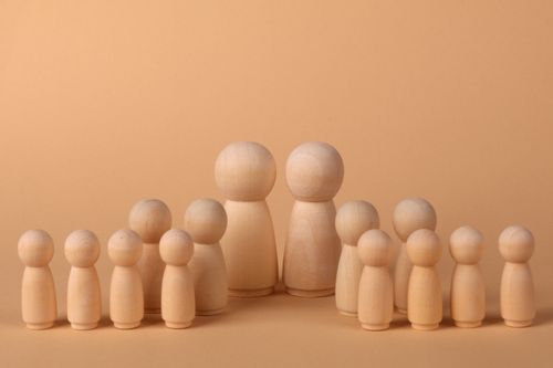 Free Minimalist display of wooden peg dolls arranged in a family group on a warm brown backdrop. Stock Photo
