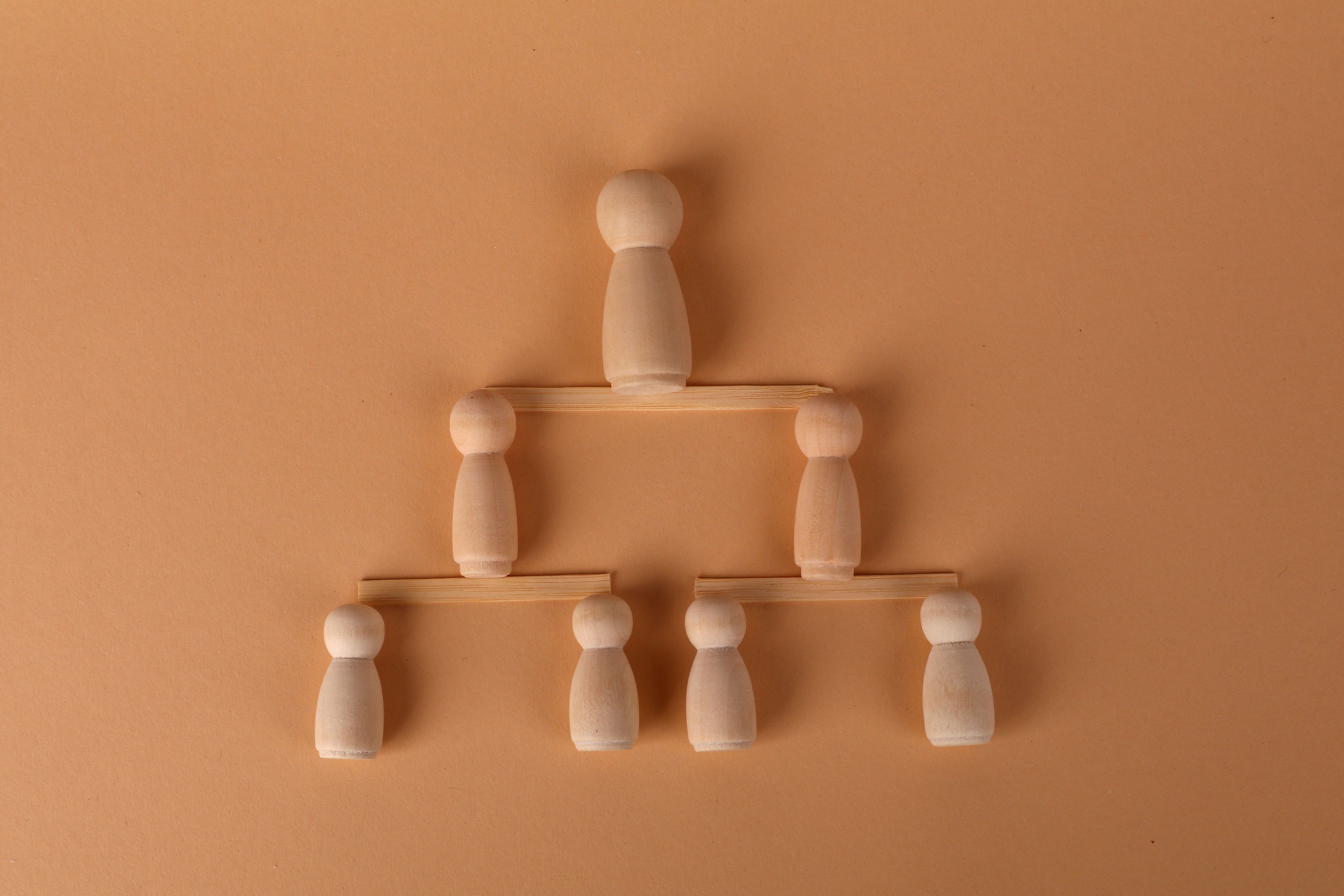 Wooden peg dolls arranged in a pyramid, symbolizing leadership and teamwork.