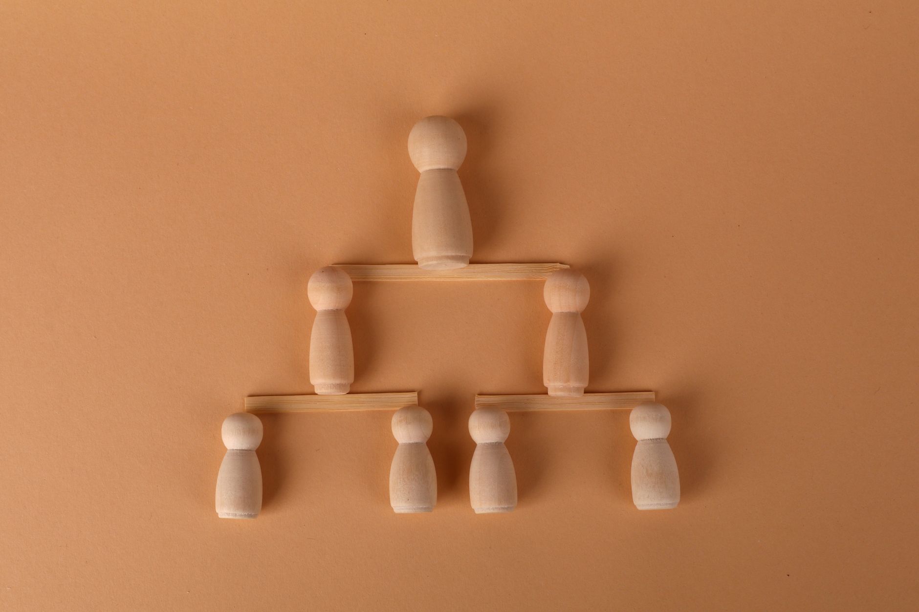 Wooden peg dolls arranged in a pyramid, symbolizing leadership and teamwork.
