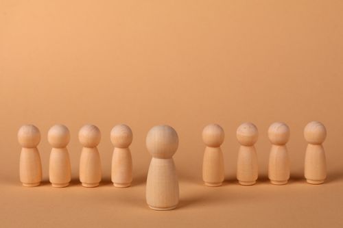Free Wooden peg figures arranged on a beige background, symbolizing community and teamwork. Stock Photo
