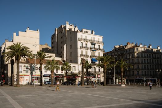 A bustling city square in Toulon, France, featuring palm trees and historic architecture.