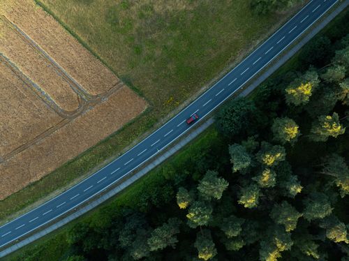 Free Stunning aerial view of a road winding through lush forest in Königslutter, Germany, during summer. Stock Photo