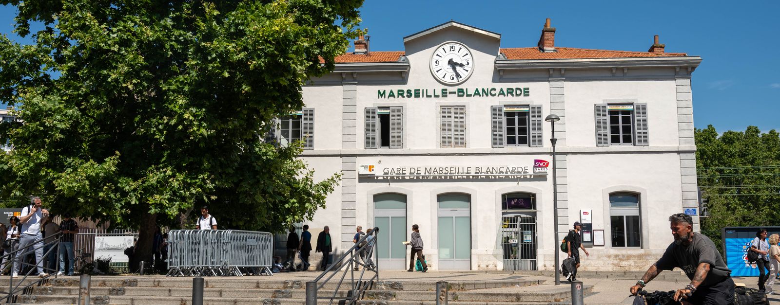 People outside Marseille-Blancarde train station in sunny Provence, France. Vibrant, dynamic scene.