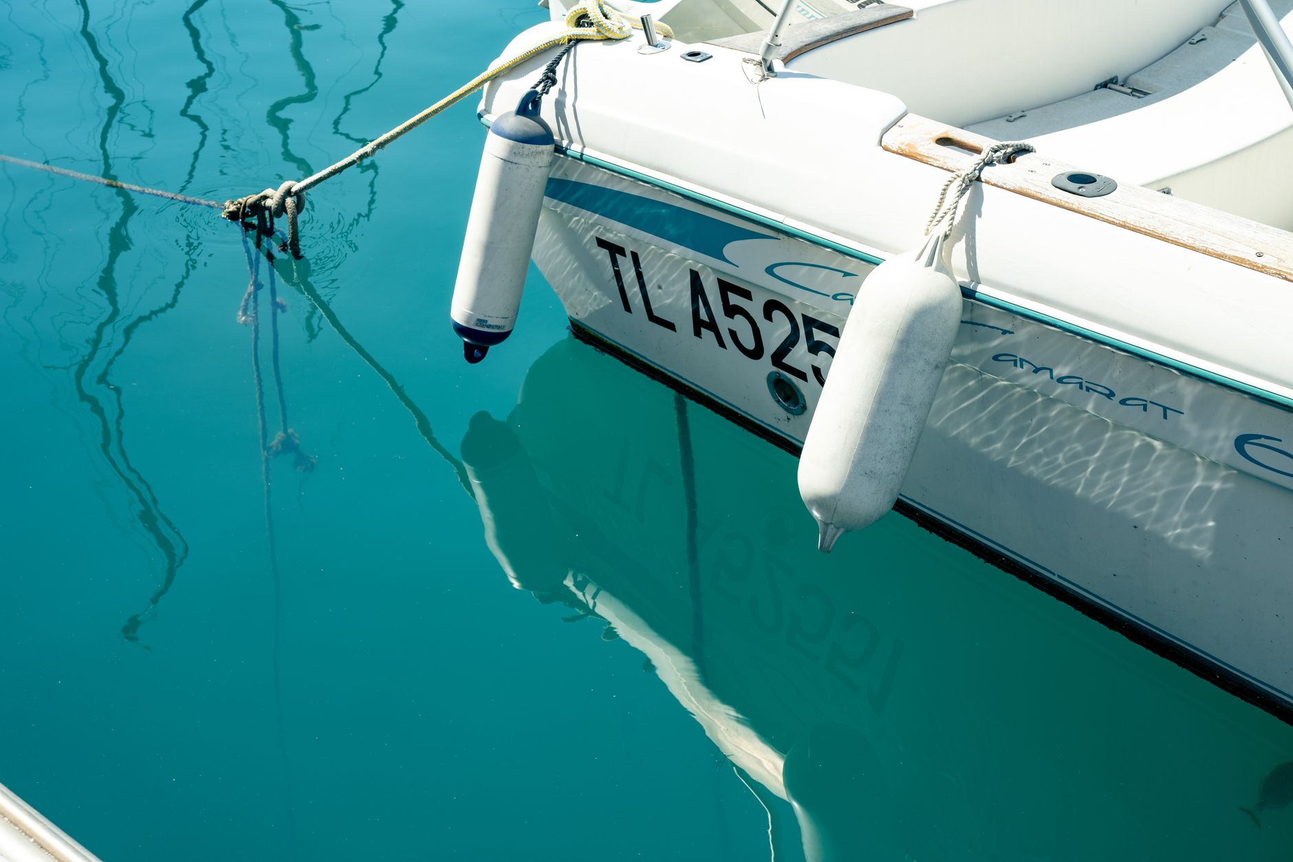 A detailed view of a moored yacht reflecting on clear water in Toulon, France.