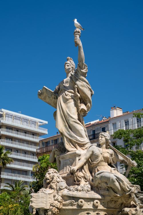 Free A grand statue in Toulon, France, with a seagull perched against a bright blue sky. Stock Photo