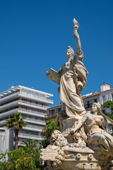 Classical statue in Toulon, France, set against modern buildings and palm trees on a clear day.