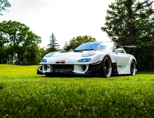 Free A sleek white sports car parked on a lush green field on a sunny day. Stock Photo