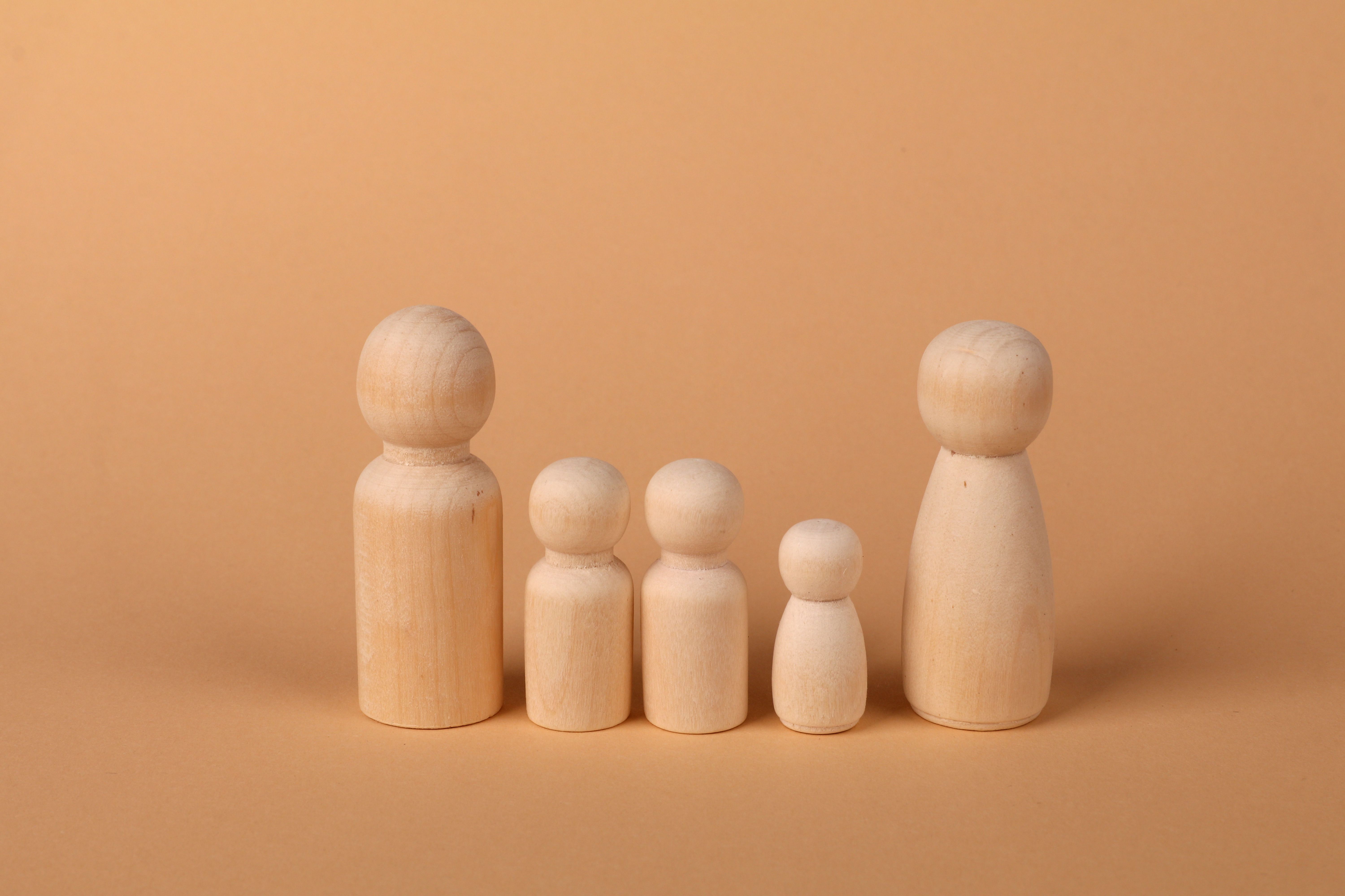 A set of wooden peg dolls arranged in a row on a beige background, depicting a family concept.