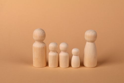 Free A set of wooden peg dolls arranged in a row on a beige background, depicting a family concept. Stock Photo