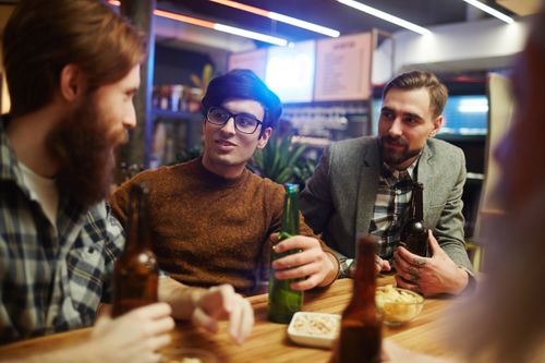 Free A group of friends enjoying drinks and conversation in a cozy pub. Stock Photo