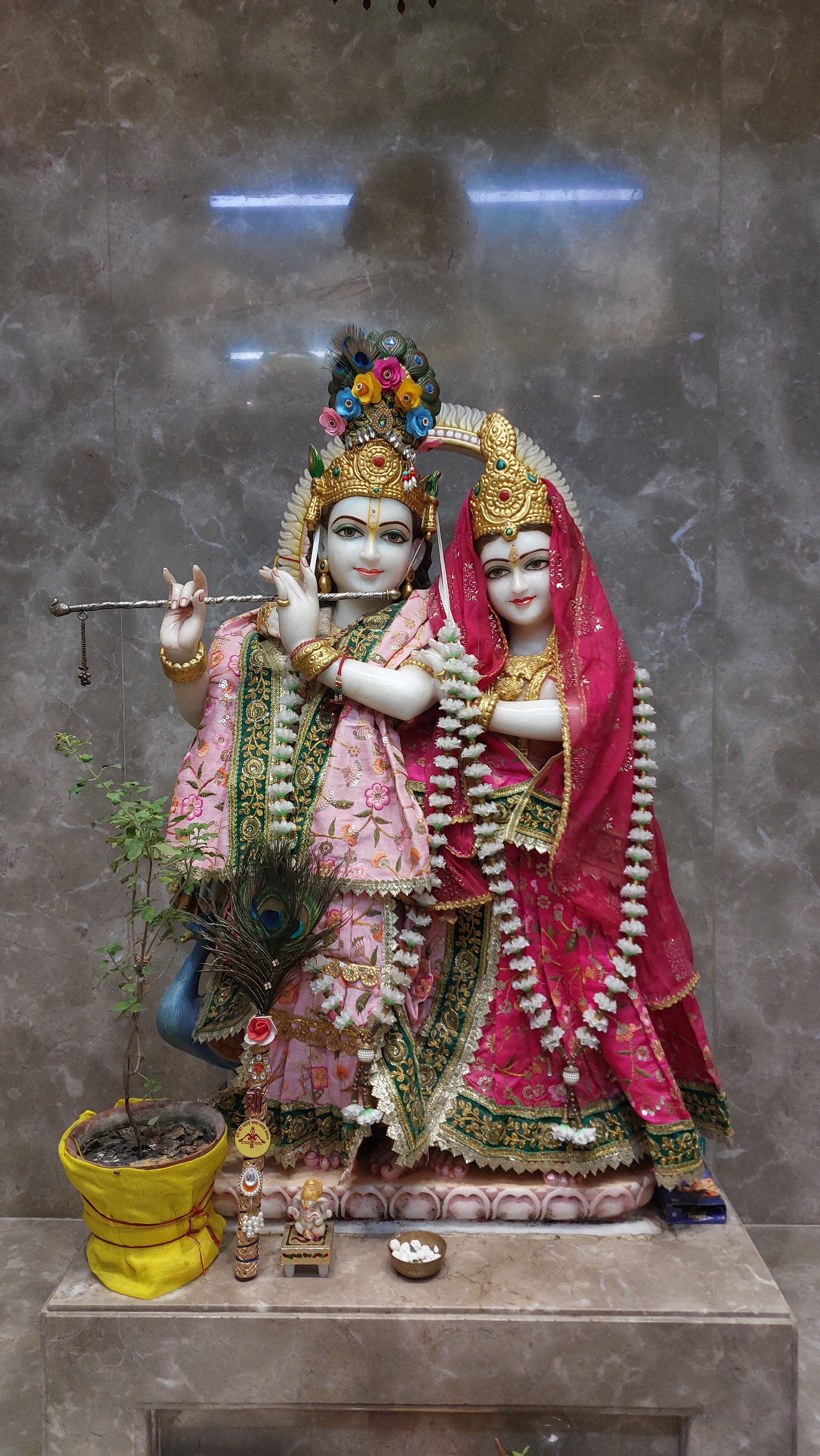 Intricately designed Radha and Krishna statues in traditional attire within a sacred temple setting.