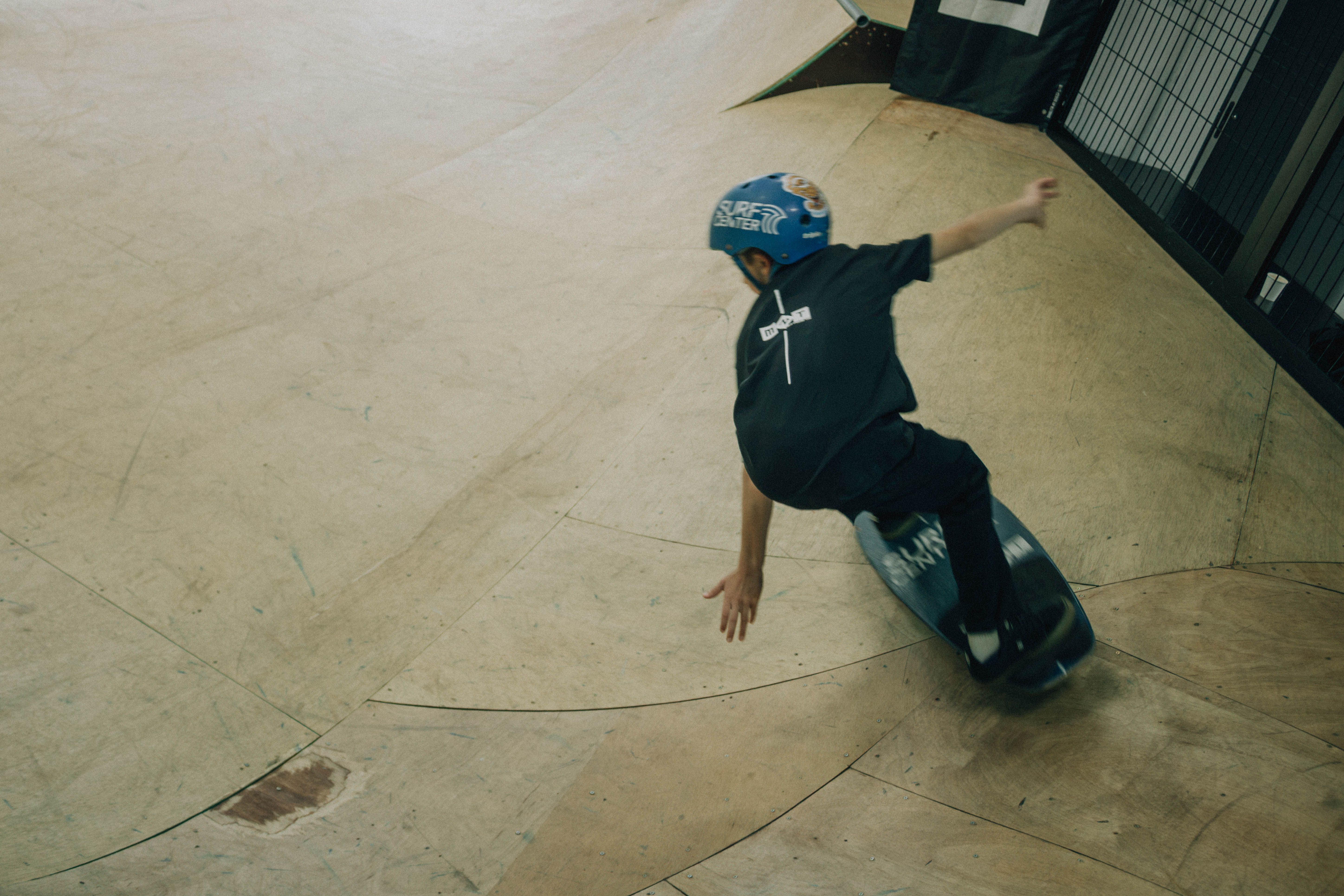 Dynamic shot of a child skateboarding on a curved ramp indoors.