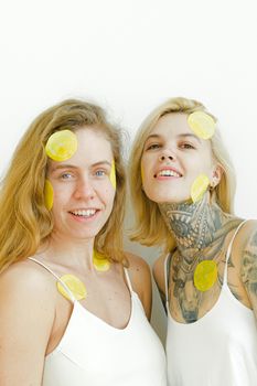 Happy women wearing casual clothes smiling while having procedure for skin and looking at camera on white background