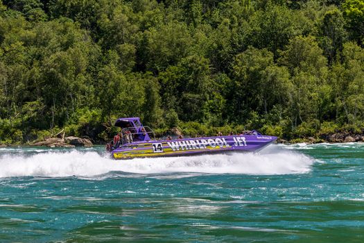 Experience the excitement of a Whirlpool Jet ride across scenic waters with lush forest backdrop.