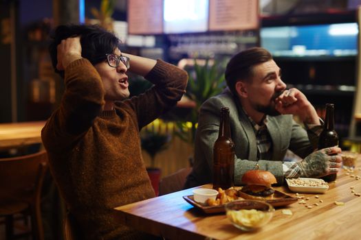 Man Holding his Head at a Bar