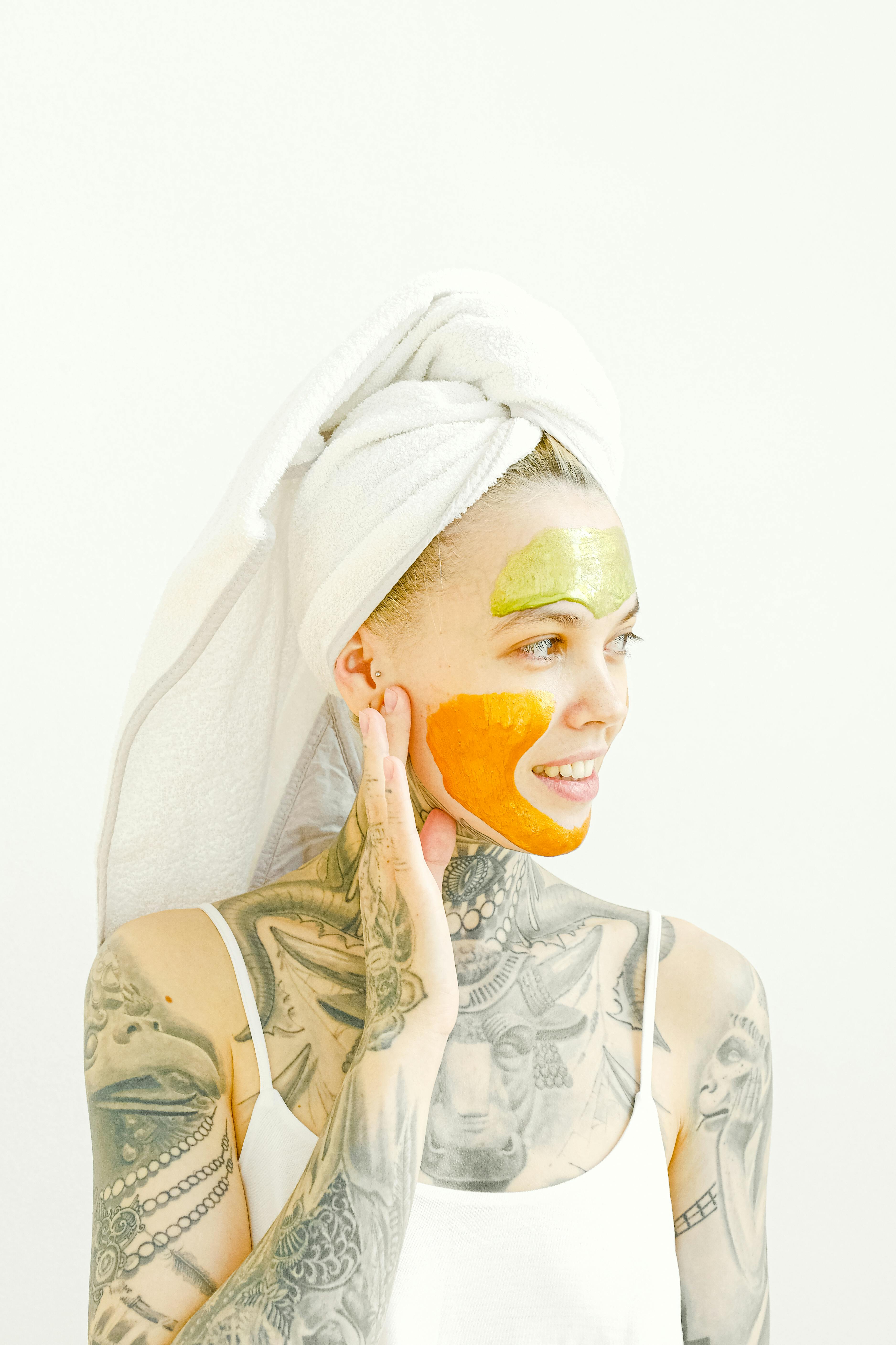 Woman with tattoos removing collagen mask from face \u00b7 Free Stock Photo