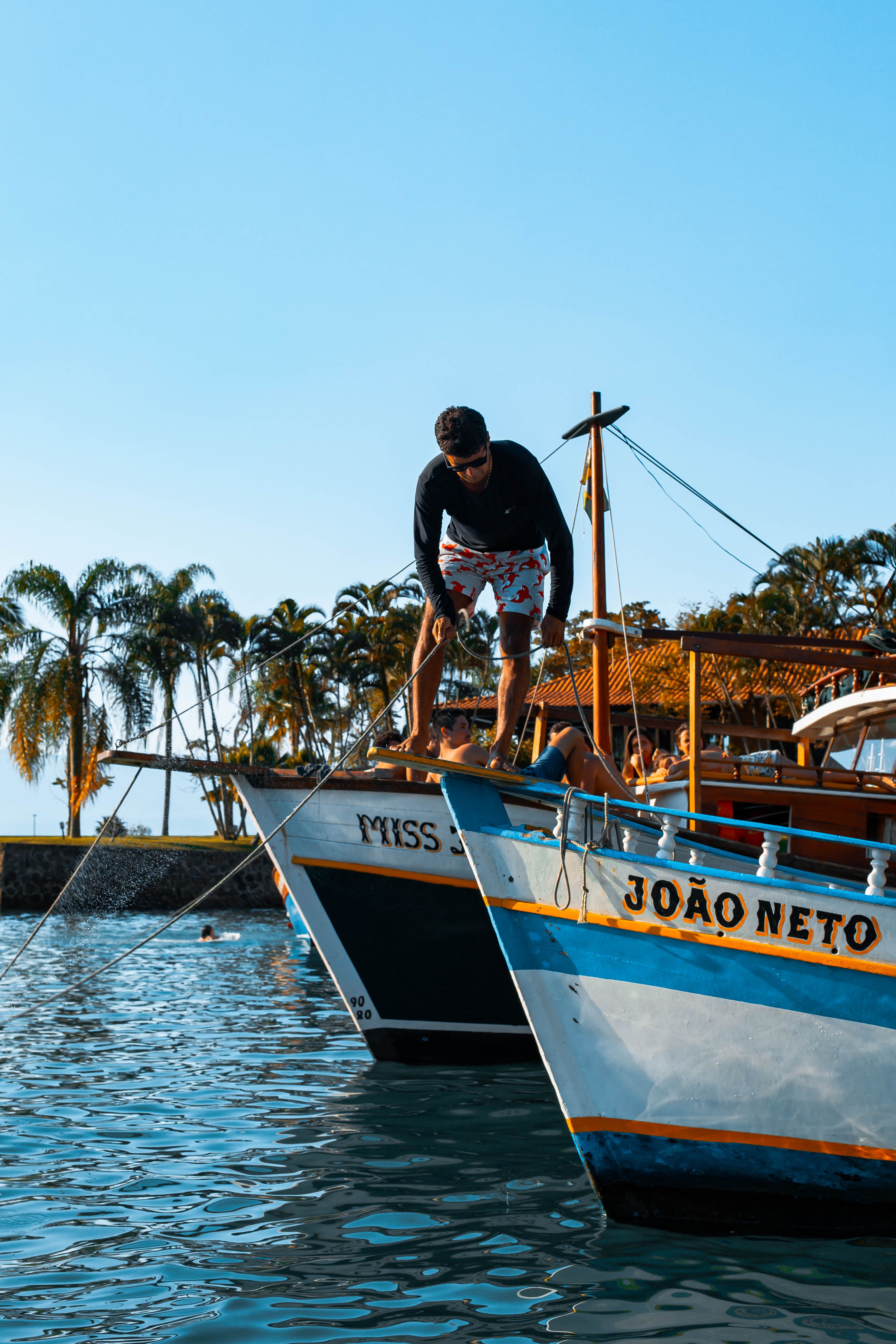 Man on boats in Paraty harbor on a sunny day, demonstrating waterfront activities in Brazil.