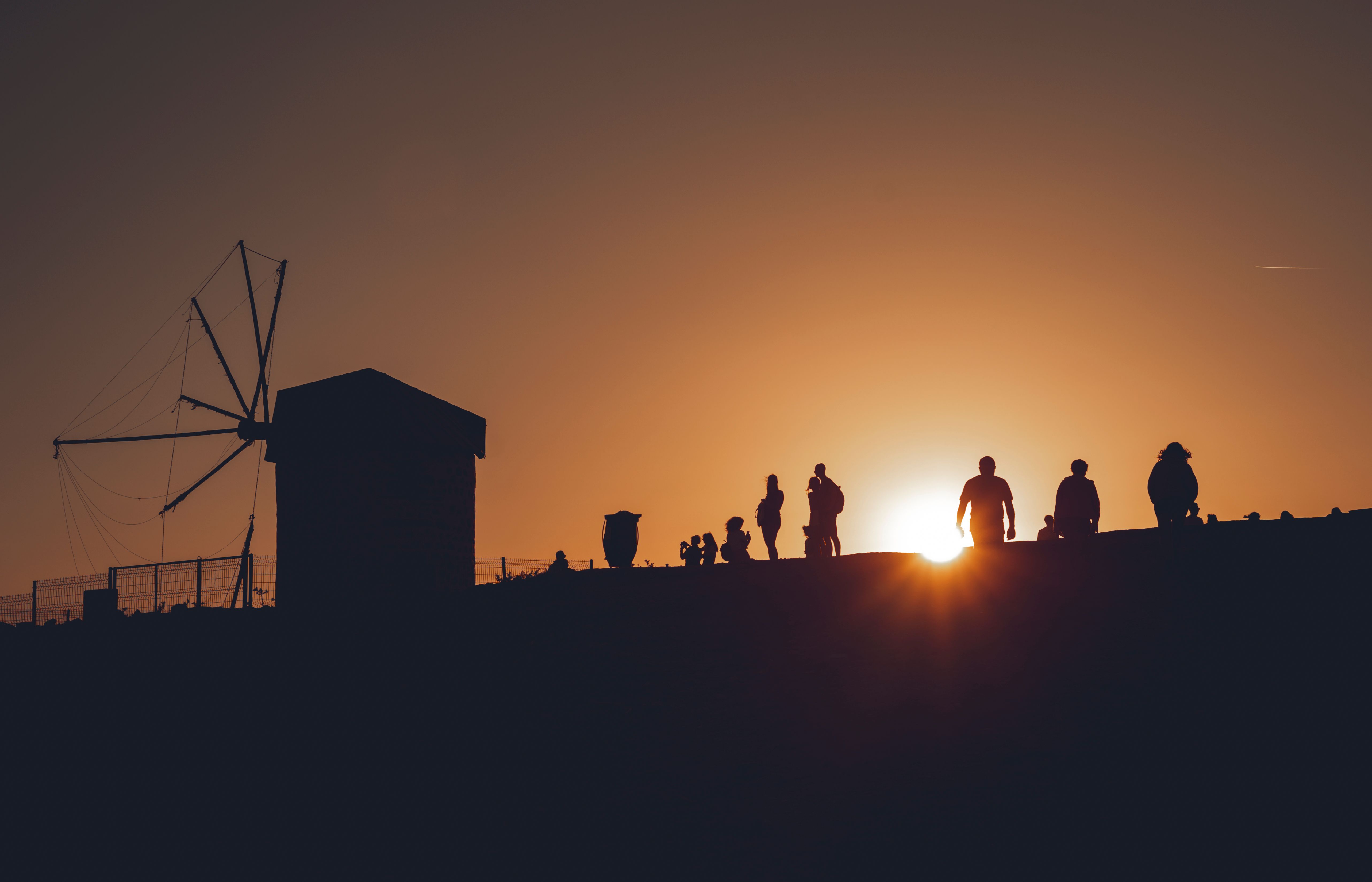 Silhouetted figures at sunset near Bodrum windmill, capturing a serene and scenic moment.
