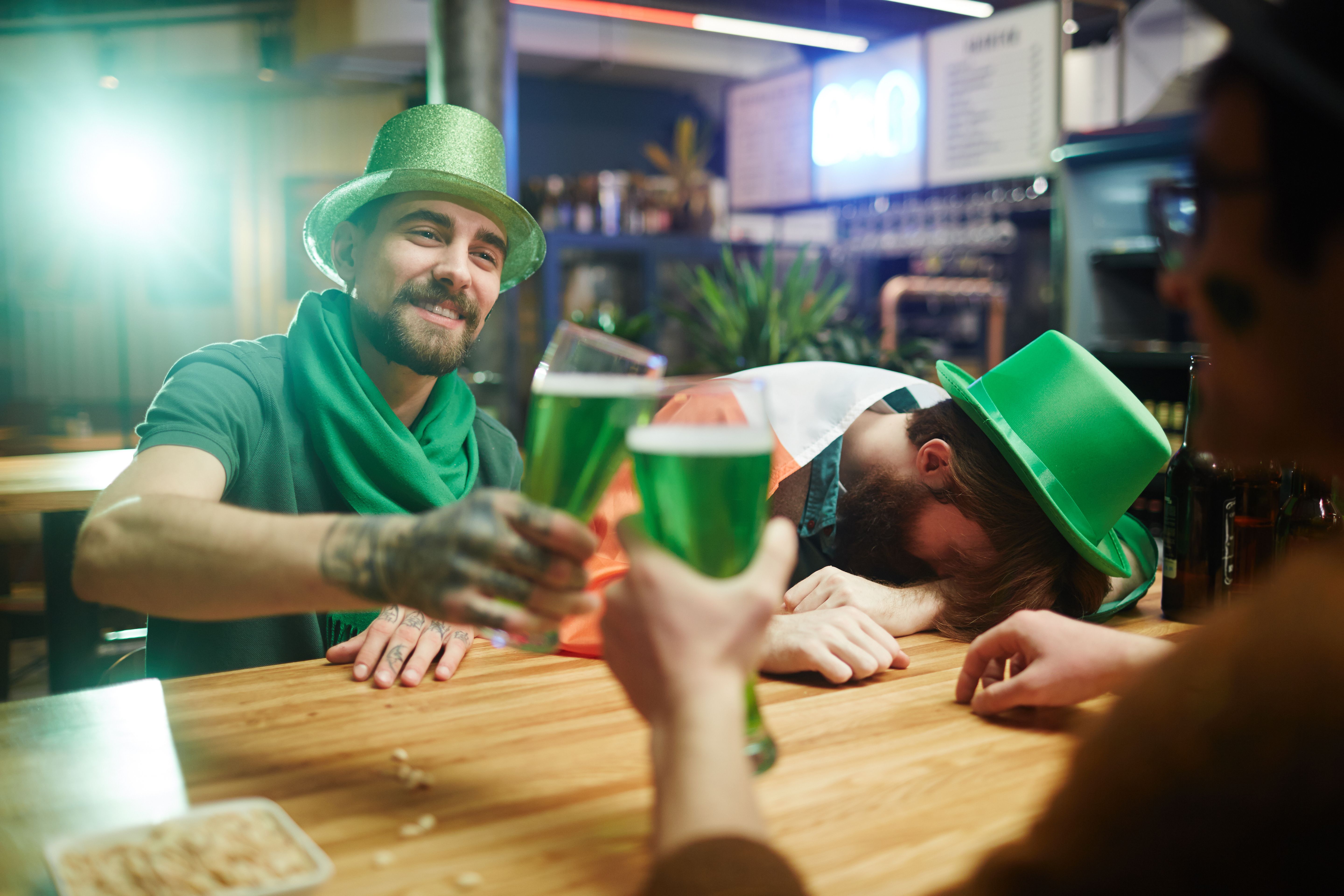 Friends enjoying green beer and festivities at a pub on St. Patrick's Day.