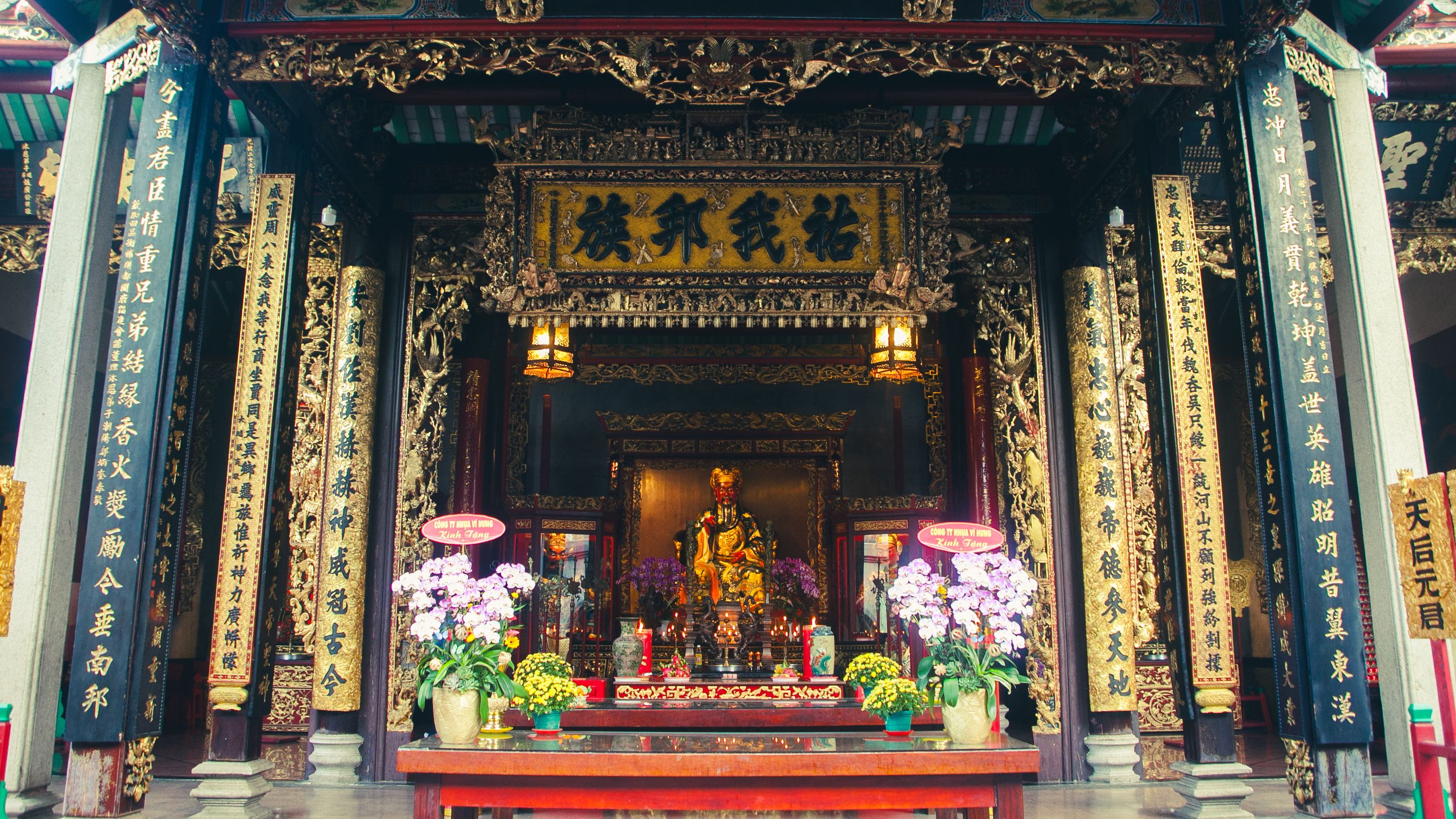 Intricate details of a temple shrine with flowers and lanterns in Ho Chi Minh City, Vietnam.