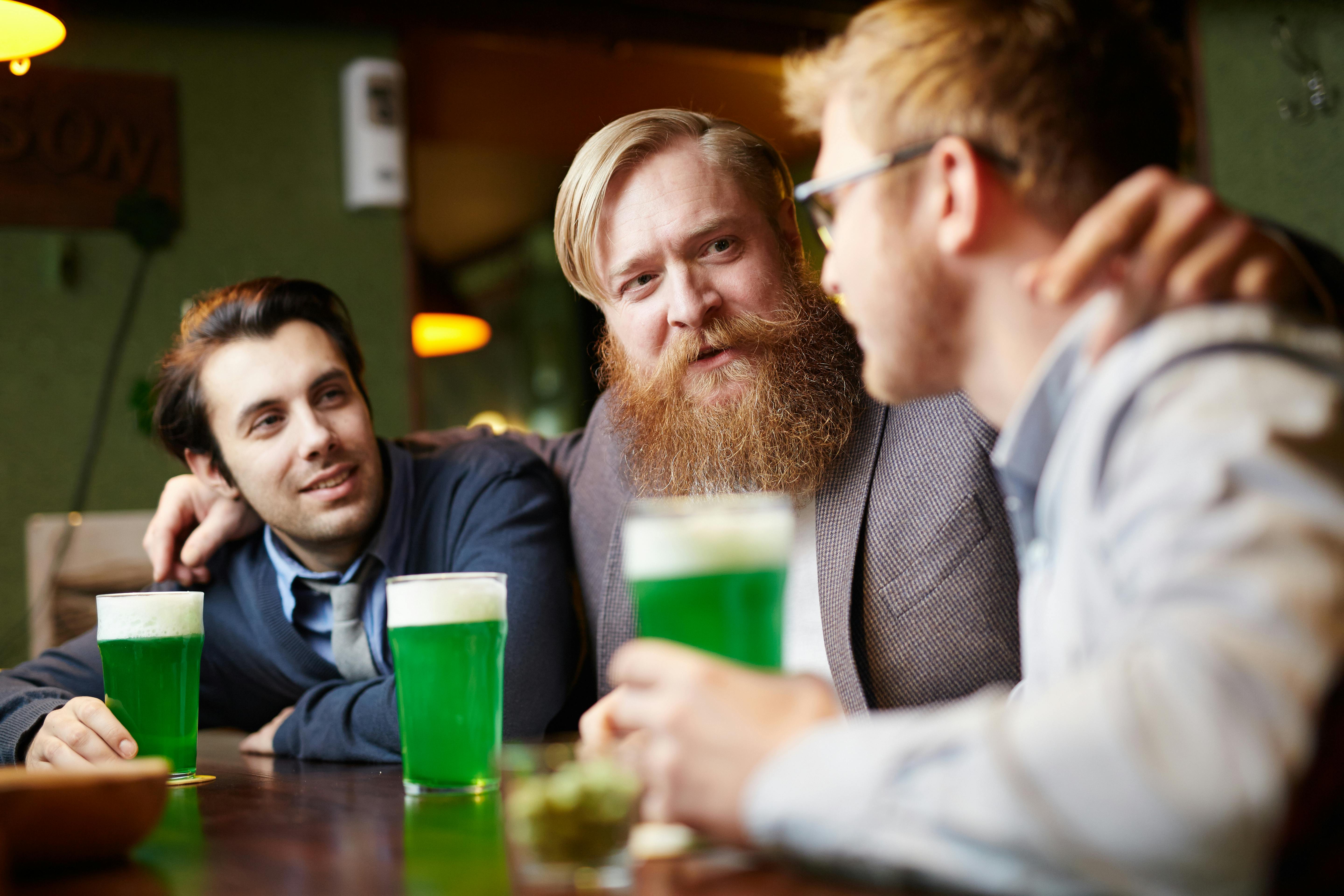 Three men having a chat over a drink. | Photo: Pexels