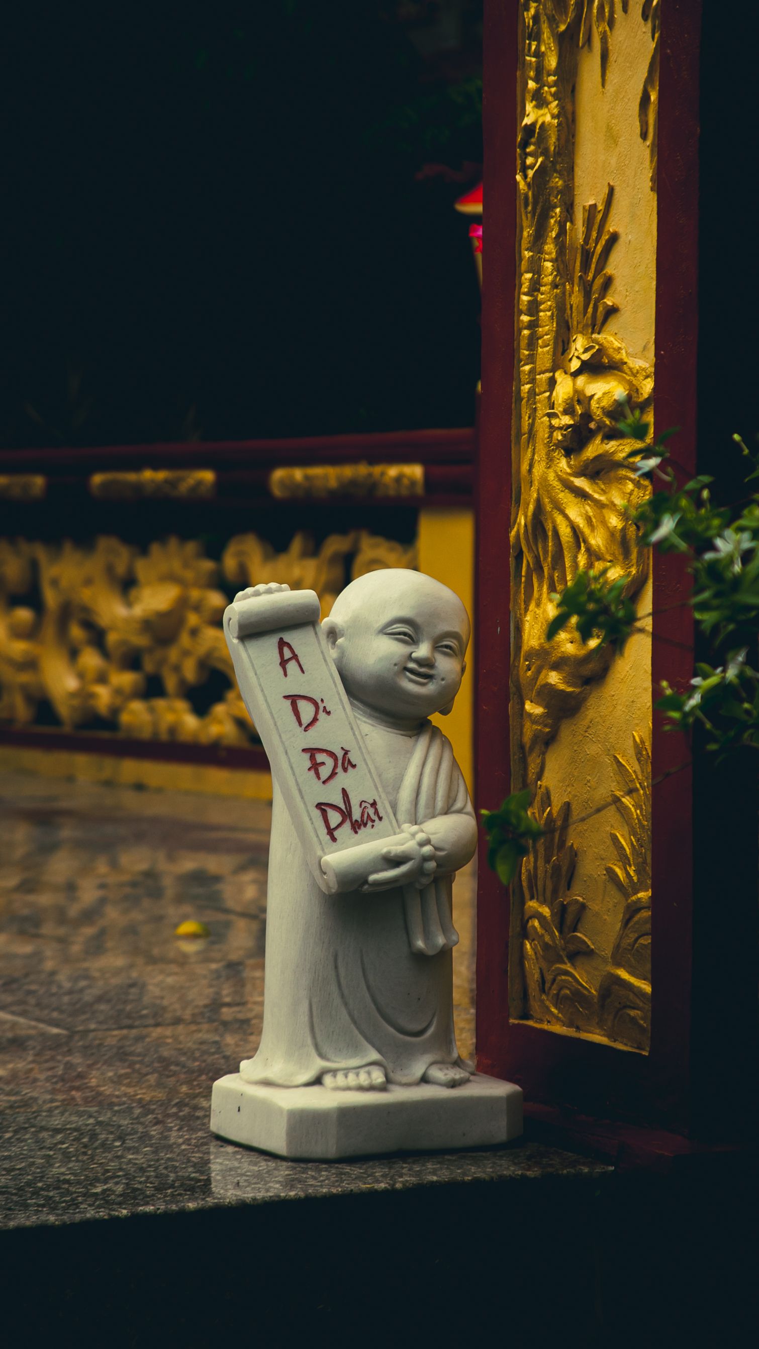 Serene stone statue near ornate golden temple entrance in Ho Chi Minh City, Vietnam.