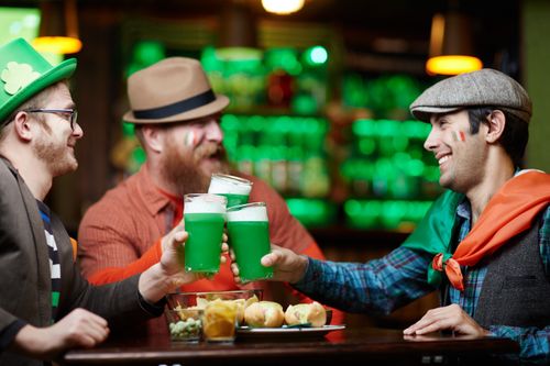 Free Three friends enjoy green beer and snacks during a festive Saint Patrick's Day celebration at a pub. Stock Photo