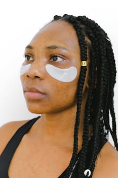 一位扎着辫子的年轻女子，戴着黑色眼罩，站在白色背景前