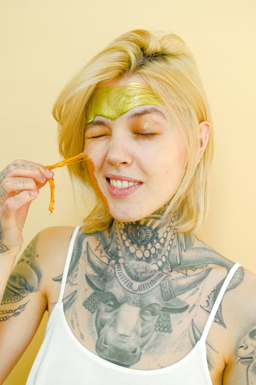 Free Young tattooed woman pulling off facial mask Stock Photo