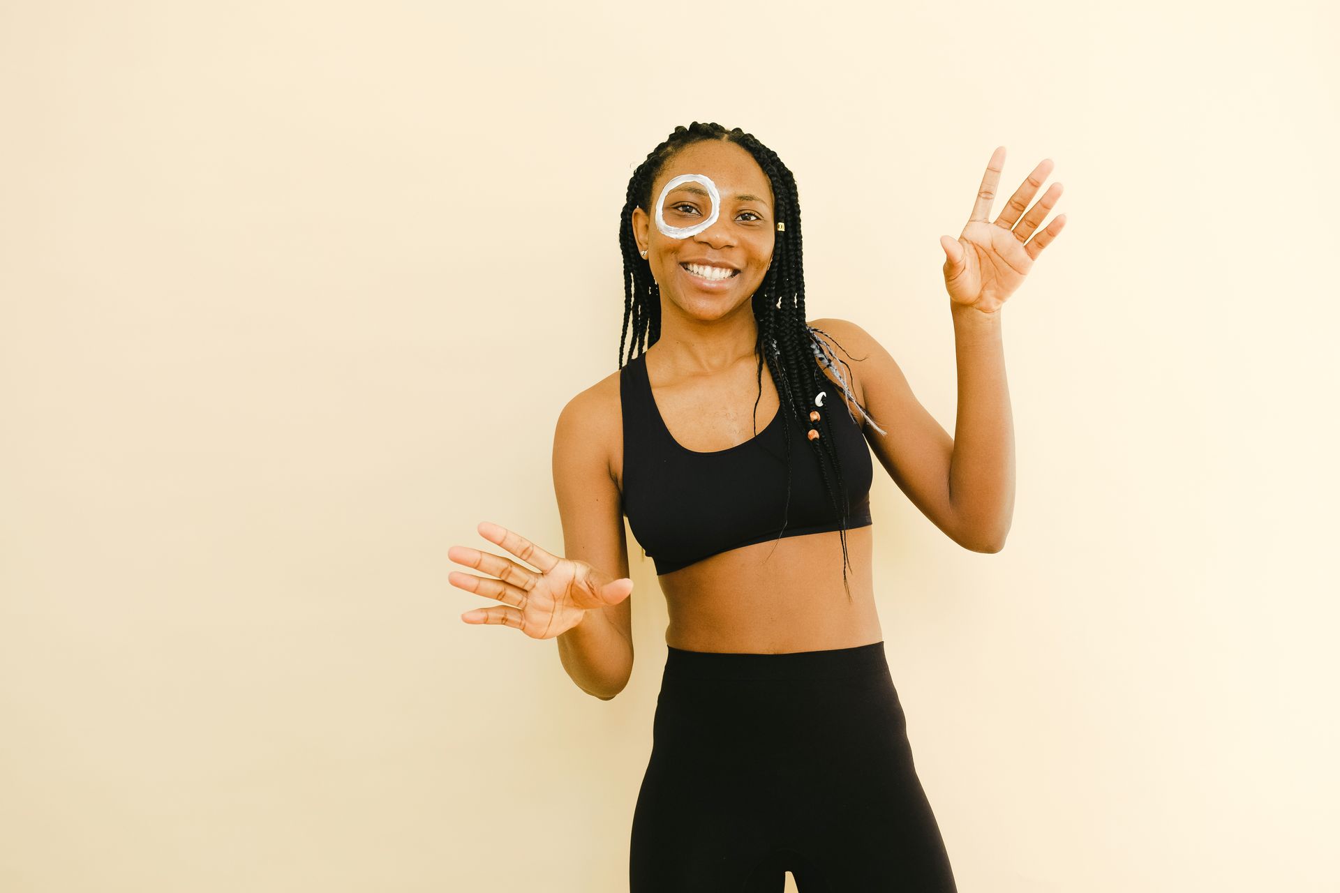 Happy African American female with white circle of moisturizing cream on face smiling and looking at camera