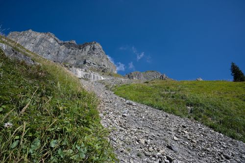 Free Steep rocky path with lush greenery leading up a mountain under a bright blue sky. Stock Photo
