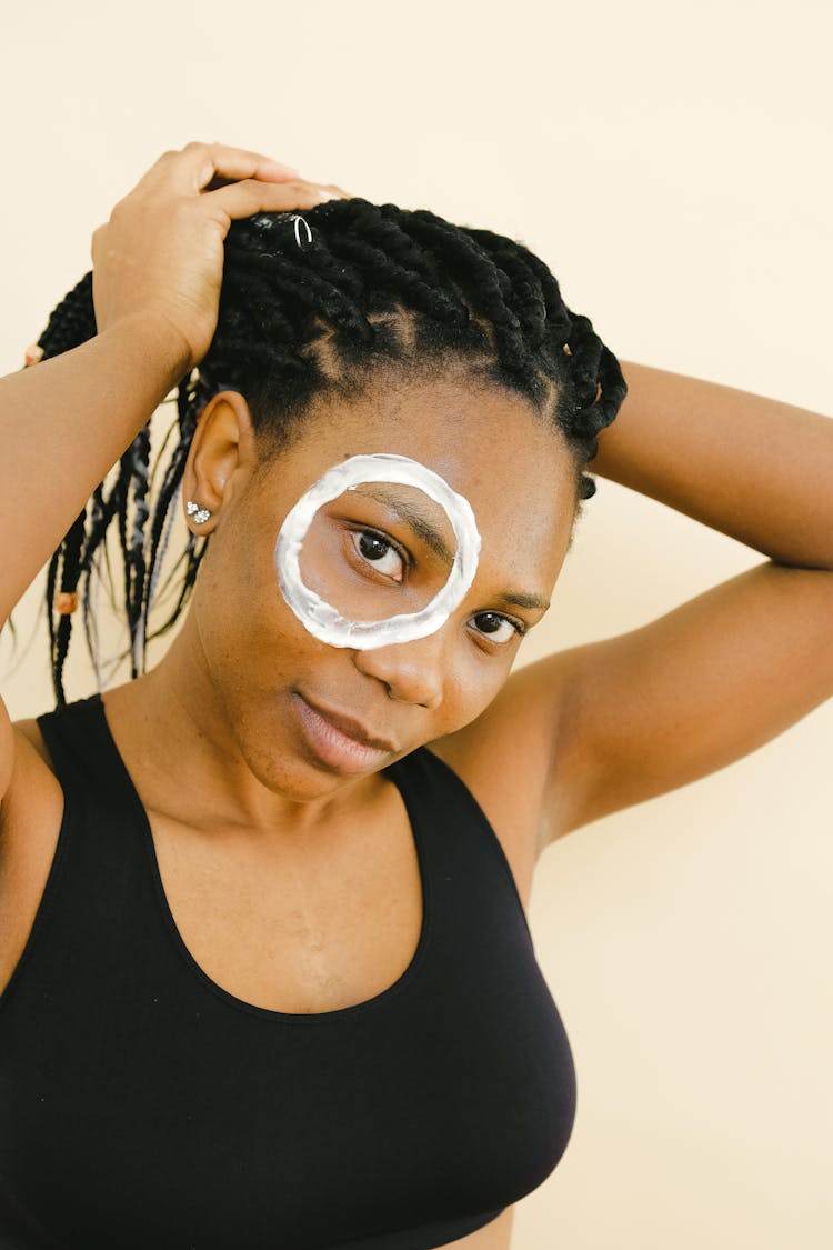 African American Woman With Lotion Around Eye Touching Hair