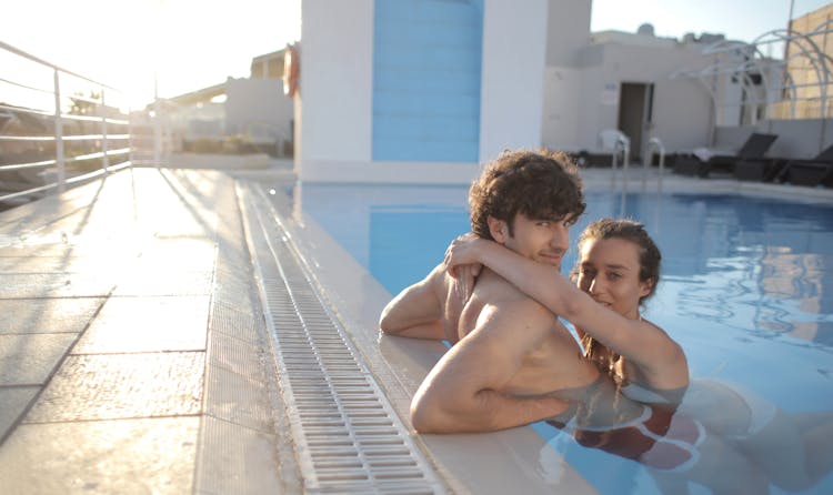 Content Couple Embracing In Swimming Pool At Resort In Summertime