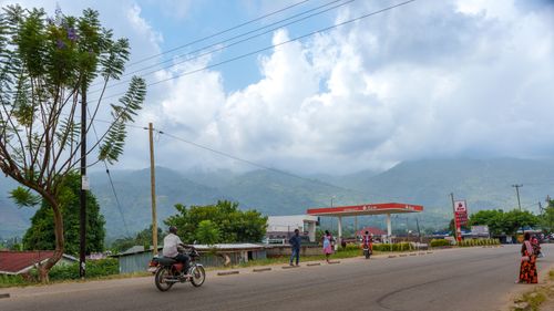 Free Lively street scene in Uganda with motorcycles and distant hills. Captures local life. Stock Photo