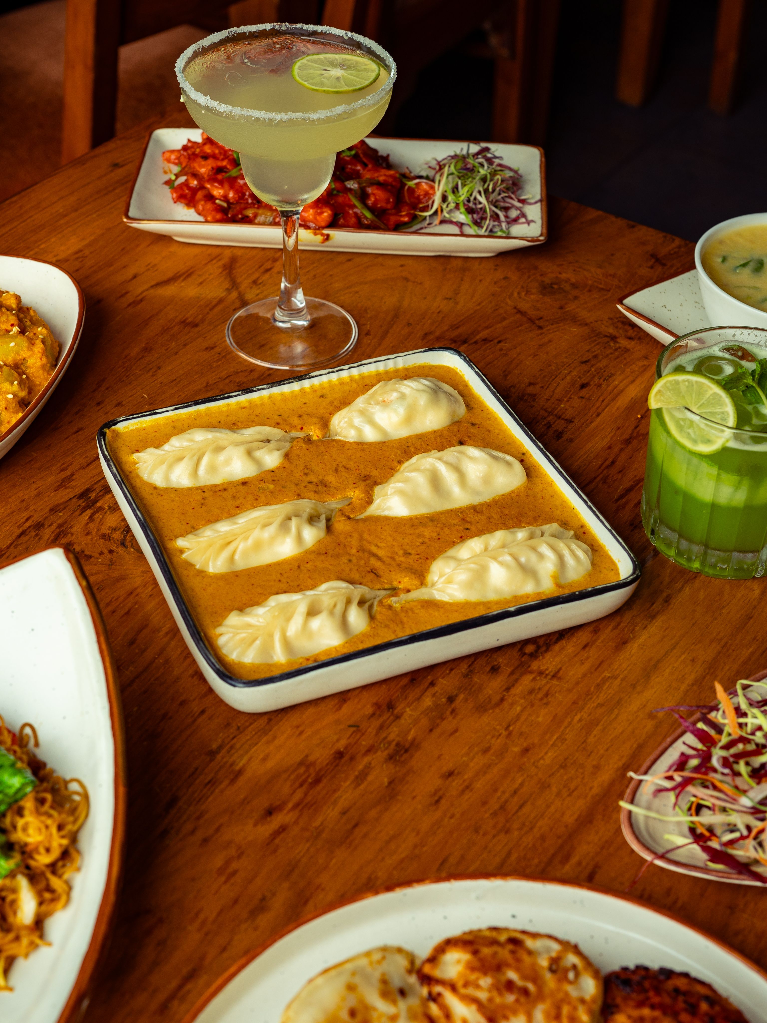 A vibrant spread of Asian dumplings and cocktails on a wooden table, perfect for a culinary delight.