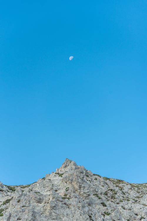 Free A serene mountain peak in Abruzzo, Italy with a clear blue sky and visible moon. Stock Photo