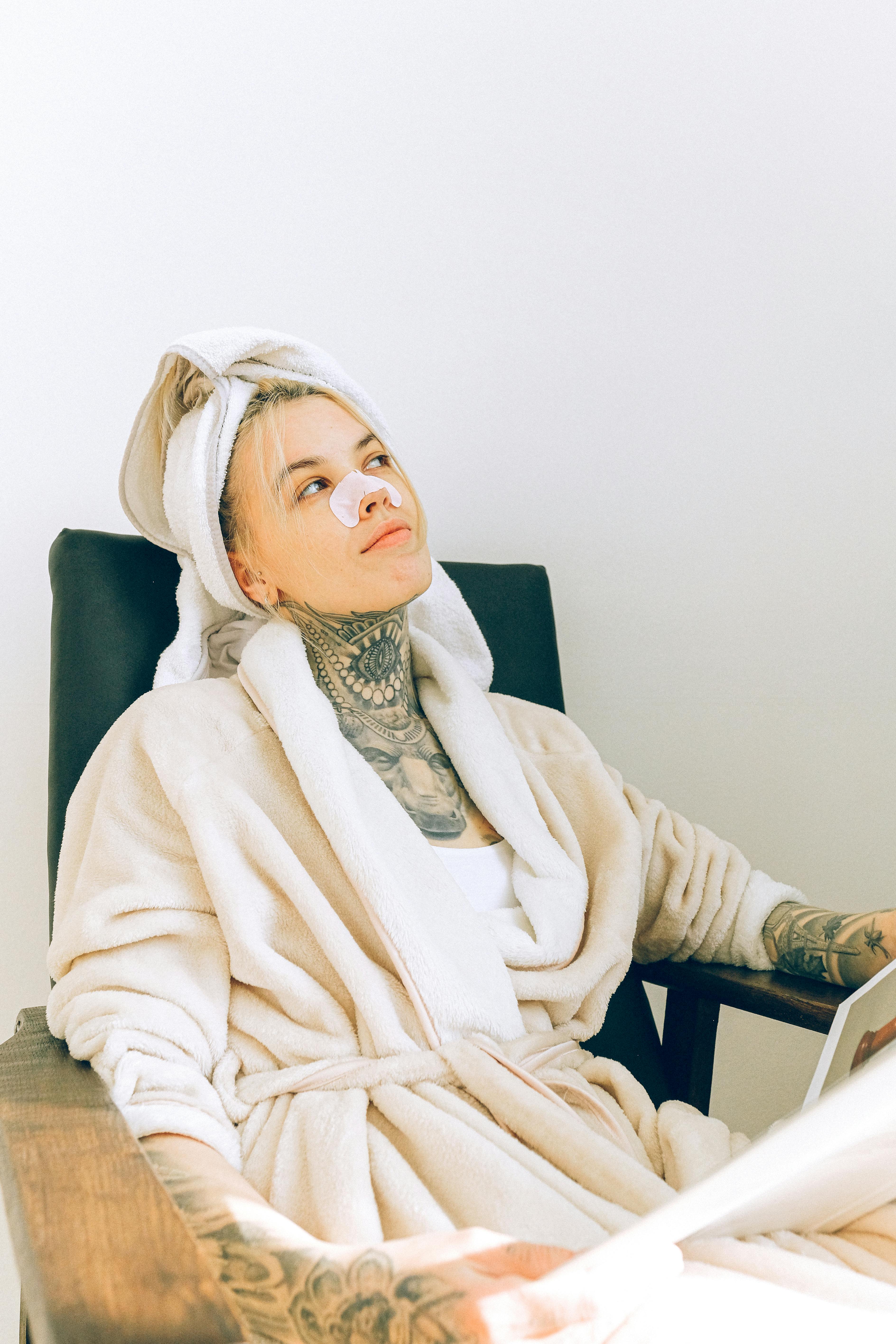 woman in bathrobe and nose mask sitting in spa salon