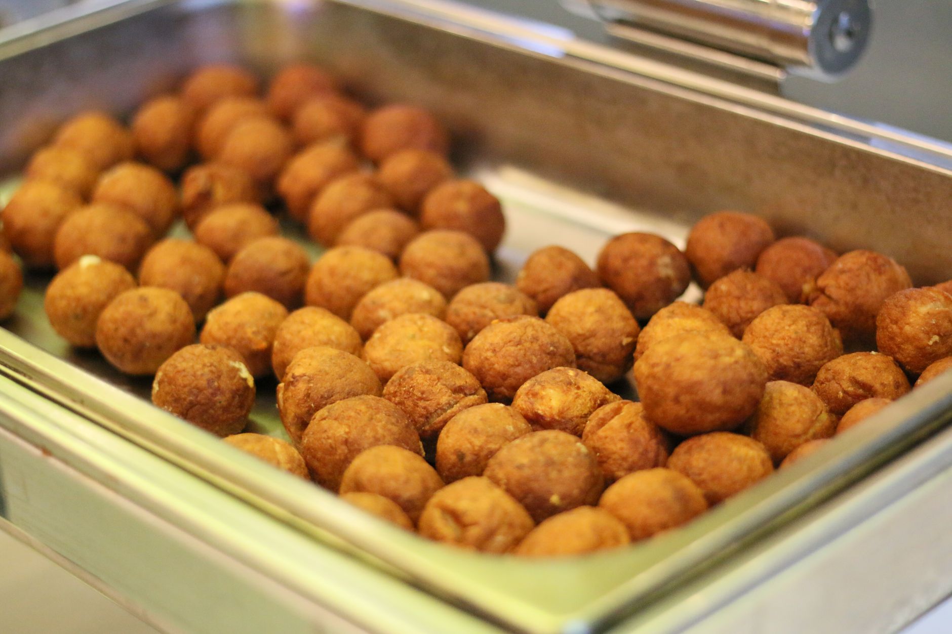 Close-up of crispy fried falafel balls in a buffet tray, perfect for catering.
