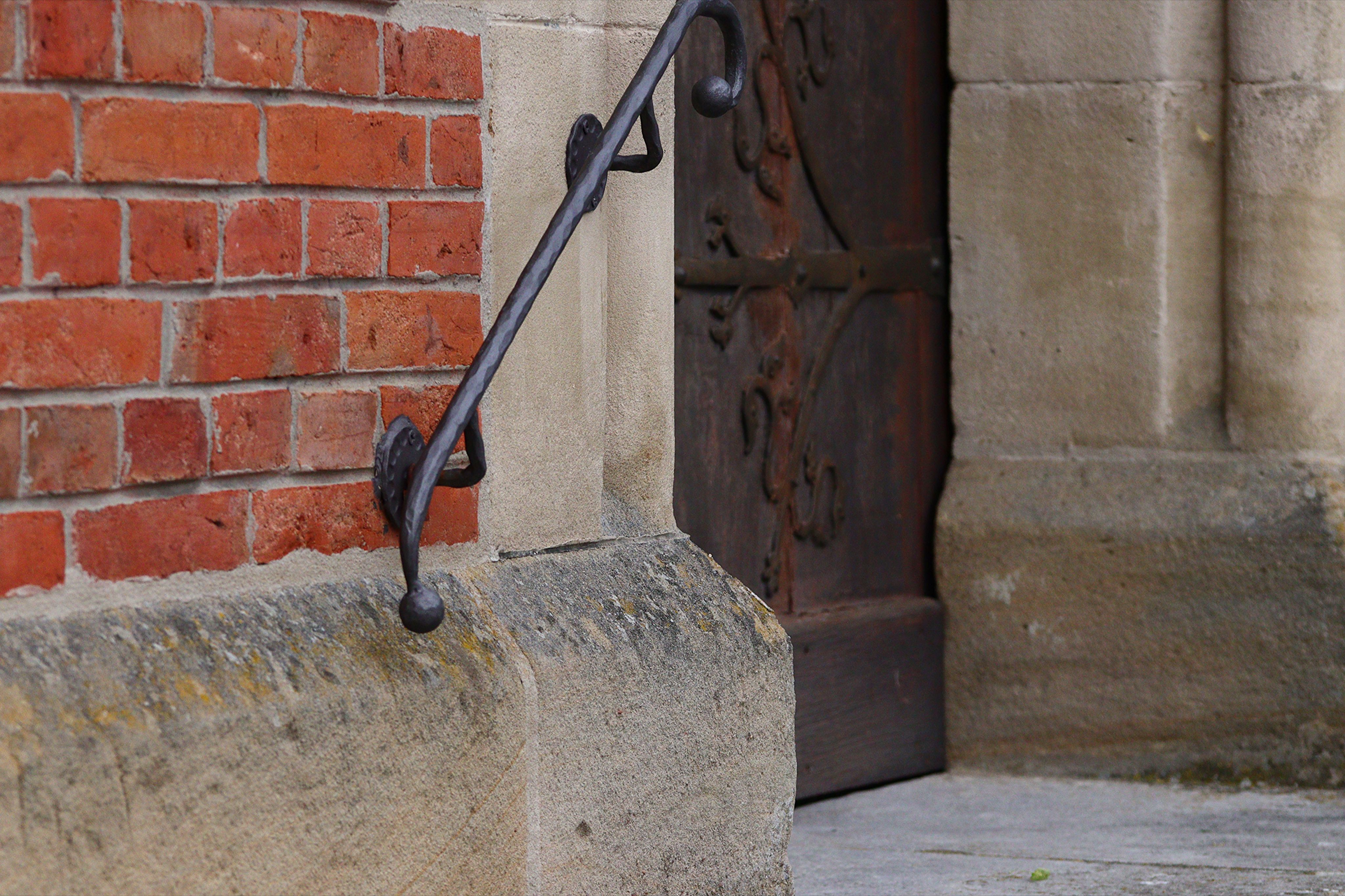 Close-up of a historic building facade with textured bricks and a wrought iron railing in Herrieden, Bavaria.
