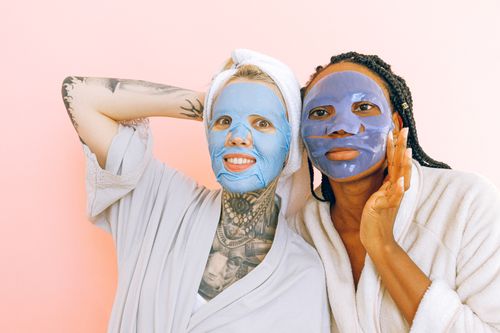 Free Women enjoying skincare routine with colorful face masks and robes. Stock Photo