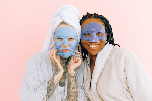 Smiling multiethnic girlfriends in collagen cosmetic masks after taking bath