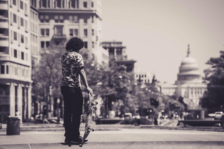 A skateboarder stands in front of the Capitol building in Washington D.C., evoking a sense of urban adventure.