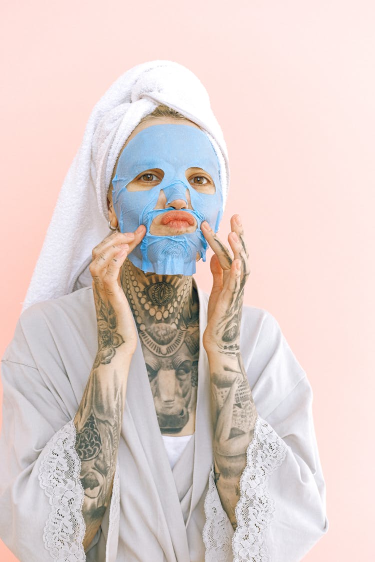 Playful Woman In Towel Applying Collagen Mask After Taking Shower