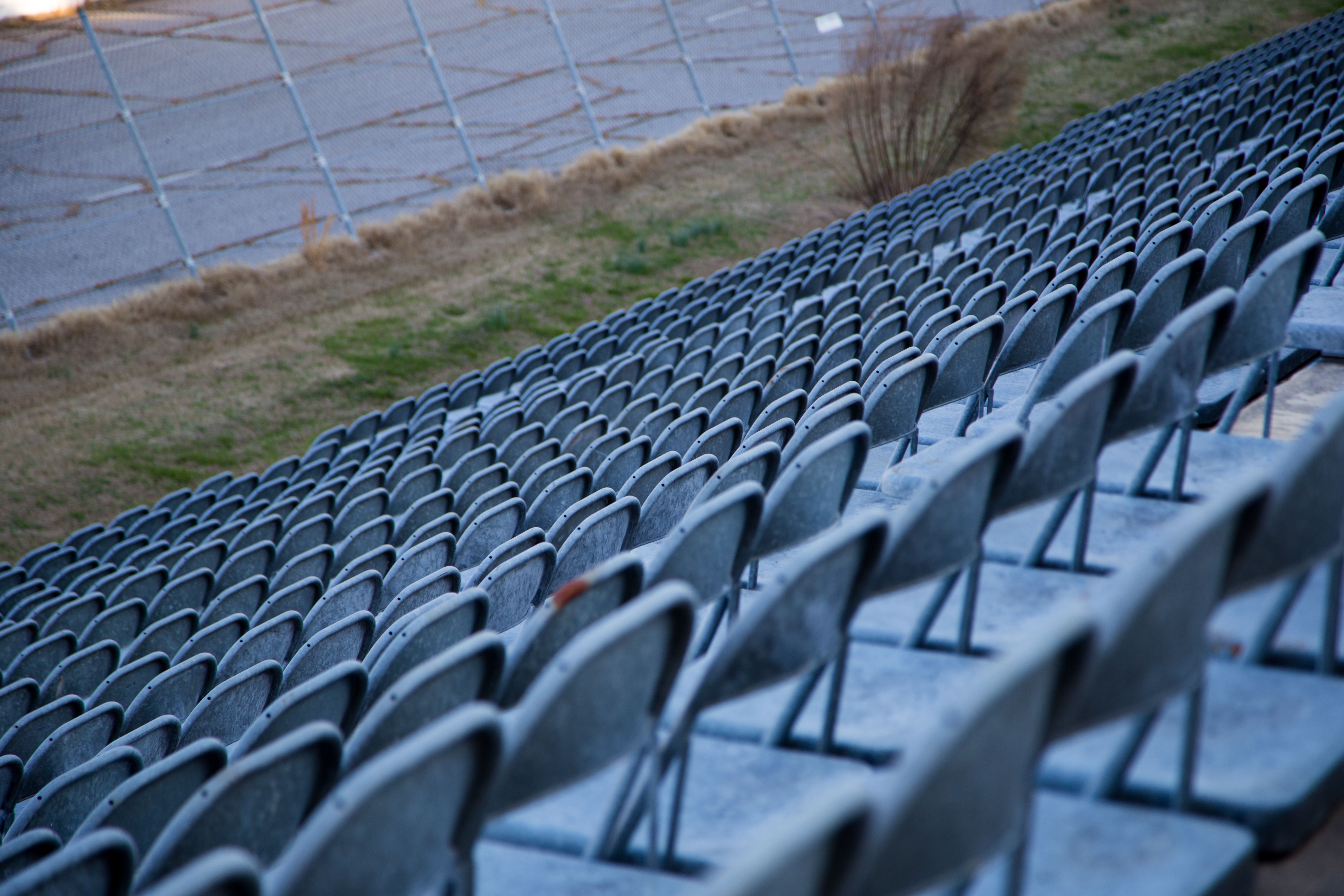 An angled view of empty metal stadium seats with a weathered look, highlighting open space.
