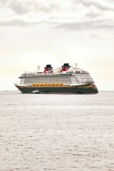 A large cruise ship sails calmly on the open sea under a cloudy sky.