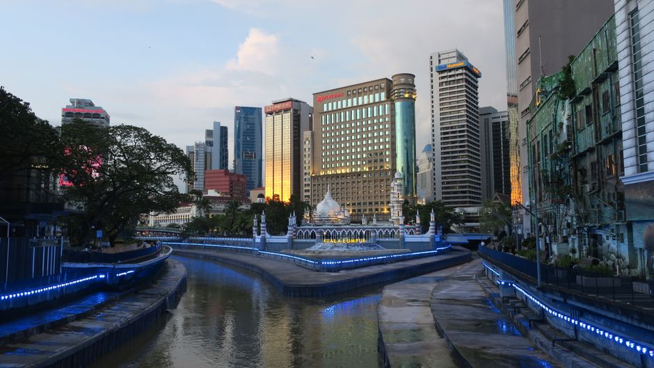 A captivating view of Kuala Lumpur's skyline and river, showcasing modern architecture and evening lights.