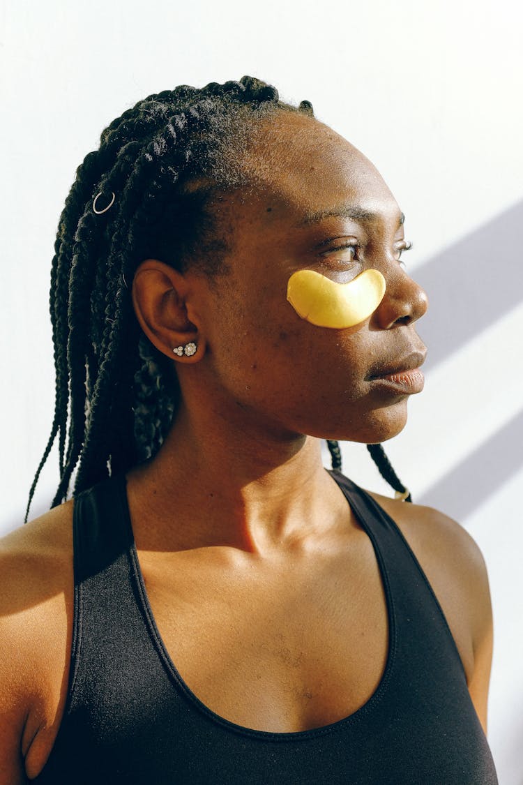 Young Black Woman With Golden Patches Under Eyes During Cosmetic Procedure