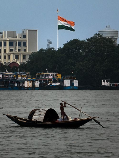 Free Scenic view of a traditional boat on the river with the Indian flag in the background, Kolkata. Stock Photo