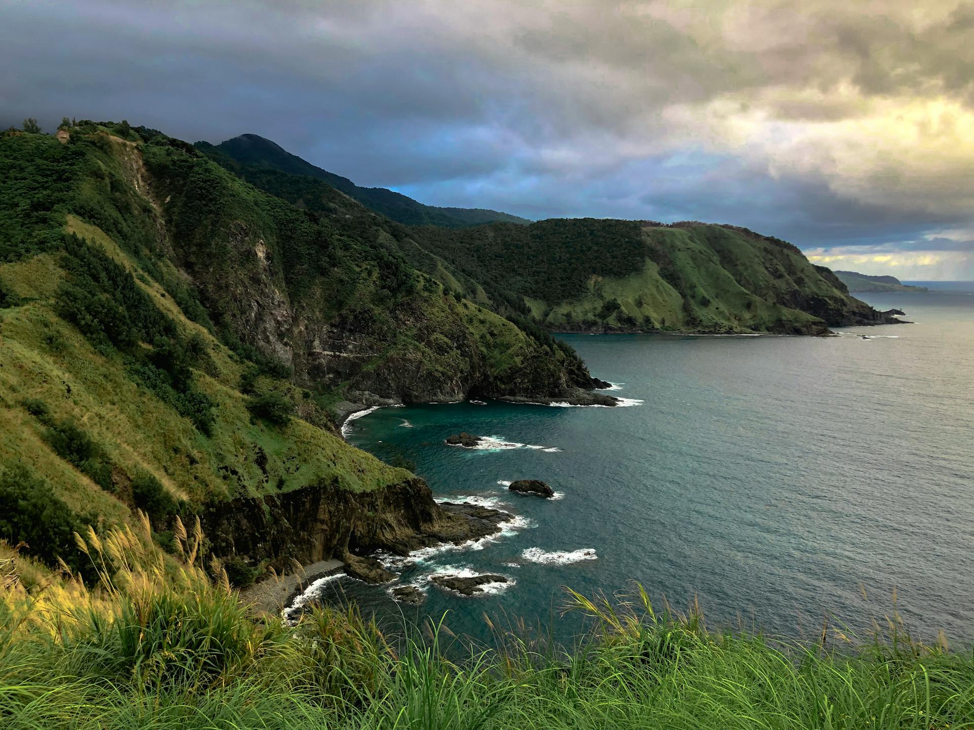 Explore the stunning coastal cliffs of the Philippines with lush greenery and ocean views.